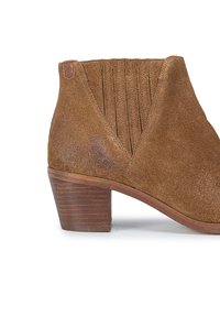 Botín de ante marrón con un diseño tapered, que presenta pliegues verticales en la parte trasera y un tacón de madera apilada.