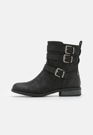 Black ankle boot made of textured synthetic material. Features three wide straps with metallic buckles and a low stacked heel.