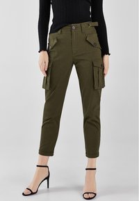 Olivově zelené cargo kalhoty slim fit, s bočními kapsami s překrytím, zapínáním na knoflíky a pasem s opaskem. Stretch materiál.