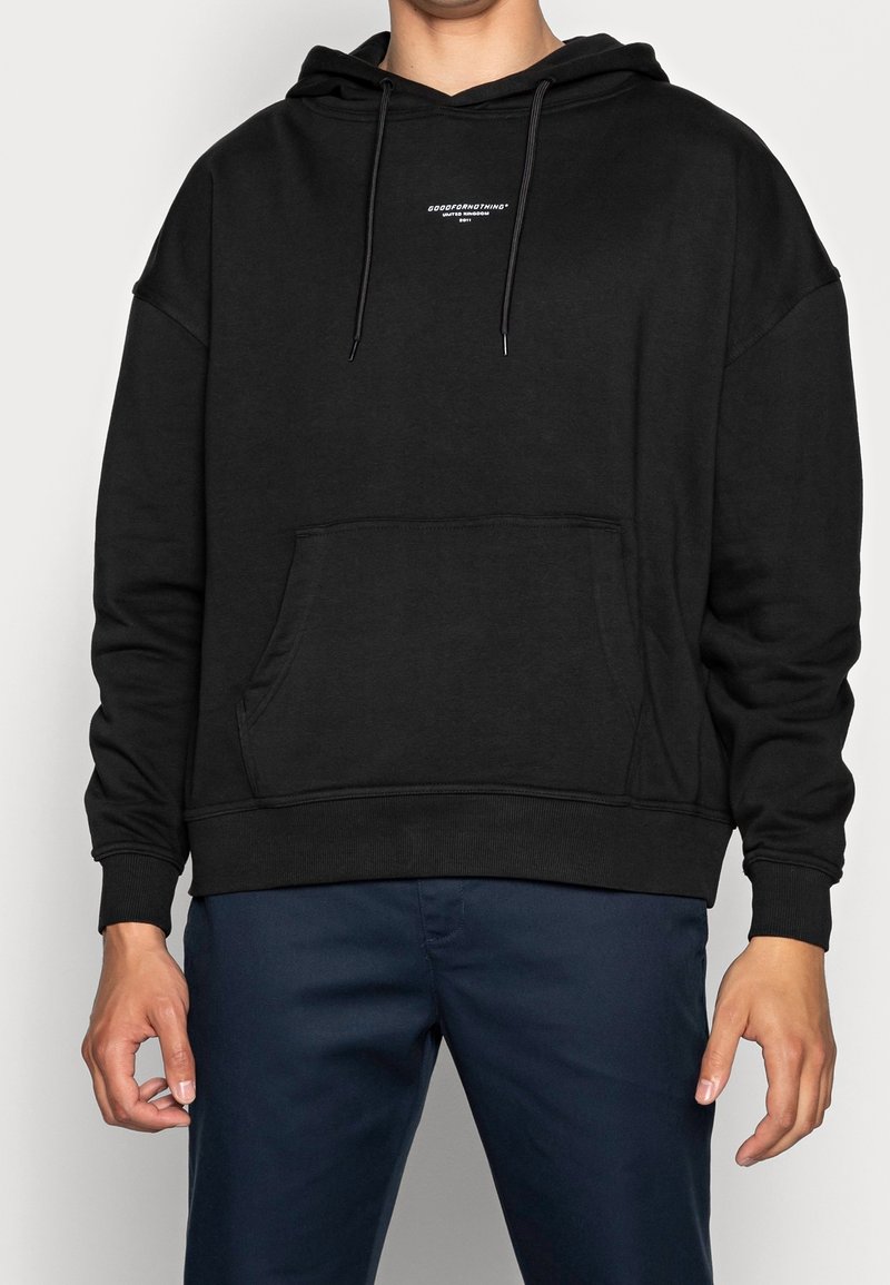 Sweat à capuche noir en mélange de coton, avec une poche avant, une capuche à cordon de serrage et un petit logo sur la poitrine. Texture douce, design oversized.