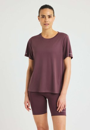 Kurzärmliges, kastanienbraunes Sportshirt mit Rundhalsausschnitt, kombiniert mit passenden kastanienbraunen Shorts. Beide Kleidungsstücke bestehen aus glattem, dehnbarem Material.