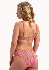 Ensemble de bikini rayé avec un motif multicolore dans les tons de rose, jaune et vert. Bretelles ajustables et liens sur les côtés du bas.
