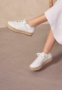 Fehér bőr sportcipők szőtt részletekkel, espadrille-stílusú juta talppal és fűzős elejével. Magasított talpú dizájn.