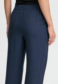 Pantalons bleu marine à rayures fines avec une taille élastique ; présentent une silhouette à jambes larges et une texture de tissu lisse. Vue arrière montrée.