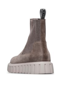 Botas de tobillo de ante en taupe con un panel de punto elástico. Presentan una suela blanca, gruesa y acanalada, y una pestaña de tirón en la parte posterior.