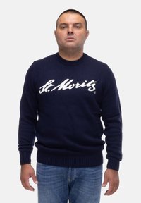Maglione lavorato a maglia blu navy con collo rotondo e polsini a costine. Presenta il testo bianco "St. Moritz" in evidenza sul petto. Vestibilità casual.