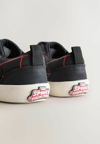Zwarte sneakers met een rood webpatroon, witte rubberen zool en zwarte stoffen accenten. Bevat een 'Spidey and Amazing Friends'-logo op de hiel.