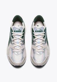 Chaussures de sport blanches et vertes en matériaux en maille et synthétiques. Elles disposent de lacets, d'une accentuation argentée et d'un logo sur la languette.