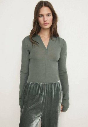 Olivovo zelený dlhý rukáv s polovičným zipsom na golieri, v súprave s mäkkými, textúrovanými šedými zamatovými nohavicami so elastickým pásom.