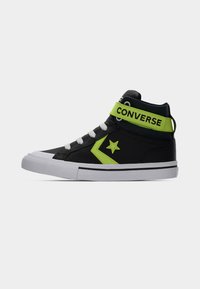 Μαύρο αθλητικό παπούτσι Converse high-top με λευκή σόλα, λευκά κορδόνια, λογότυπο νεον πράσινου αστεριού και νεον πράσινη λουρίδα αστραγάλου με το κείμενο «CONVERSE».
