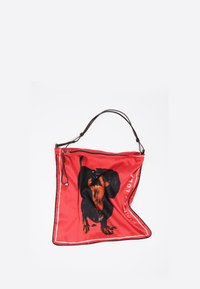 Czerwony materiałowy worek z grafiką czarno-brązowego psa, z górnym zaciąganym zamknięciem i czarnymi wykończeniami, zaprojektowany z prostą rączką.