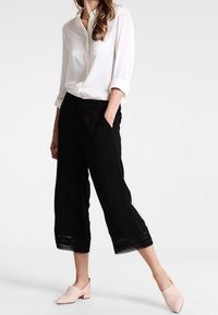 Vit långärmad skjorta, svarta cropped byxor med spetsdetaljer och rosa slip-on skor. I bomull, avslappnad passform och minimalistisk design.