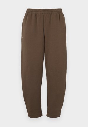 Brune sweatpants, laget av mykt stoff, med elastisk midjebånd og avsmalnende ben med en enkel hvit logo på siden.
