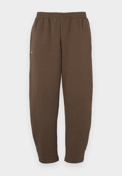 Καφέ φόρμες, κατασκευασμένες από μαλακό ύφασμα, με ελαστική μέση και στενές ποδιές, με μια απλή λευκή λεπτομέρεια λογότυπου στο πλάι.