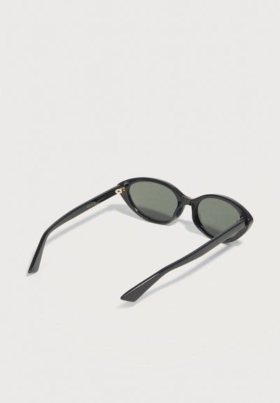 Μαύρα γυαλιά ηλίου με οβάλ πλαίσιο και σκουρούς φακούς, ανοιχτά και τοποθετημένα σε λευκή επιφάνεια, με θέα από την πίσω πλευρά.