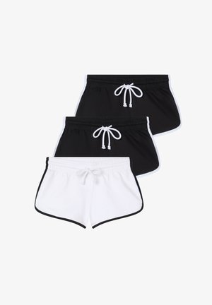 Niebieski bawełniany t-shirt z krótkim rękawem, połączony z białymi szortami na sznurki z czarnymi wykończeniami. Model stoi w casualowych butach na jednolitym tle.