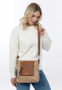 Borsa a tracolla marrone realizzata in materiale sintetico, dotata di una tasca frontale con zip, tracolla regolabile e accenti più chiari a contrasto.