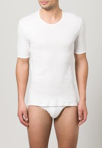 Hvid bomulds t-shirt med korte ærmer, rund halsudskæring, tætsiddende pasform, glat tekstur og parret med hvide trusser. Minimalistisk design.