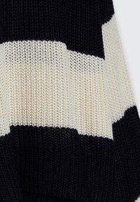 Maglione a maglia con ampie strisce orizzontali nere e crema, realizzato in filato testurizzato con una vestibilità ampia e dettagli a coste all'orlo.