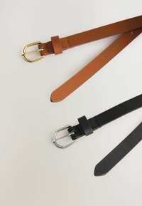 Deux ceintures : une en cuir marron avec une boucle en or, et une en cuir noir avec une boucle en argent. Les deux ont des textures lisses et des extrémités pointues.