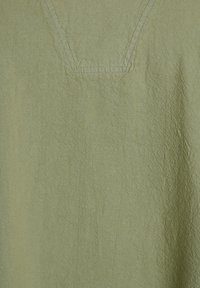 Indumento verde chiaro caratterizzato da un tessuto testurizzato, design a V e dettagli di cucitura visibili. Aspetto morbido e casual.