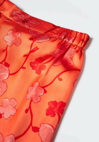 Felrood stoffen met bloemenpatronen in verschillende tinten rood. Elastische tailleband aan de bovenkant, gladde satijnen textuur.