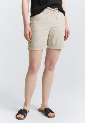 Beige stribede shorts med elastisk talje, snor, sidelommer og opdrukne manchetter, parret med mørke slip-on sandaler.