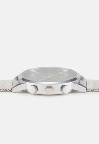 Montre-bracelet en argent avec un bracelet en maille, cadran rond noir, deux boutons-poussoirs, couronne texturée et index lumineux.