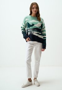 Pull en tricot avec un design de montagne et de forêt en teal, marine et crème. Doté de manches longues, d'un col rond et d'une coupe décontractée.