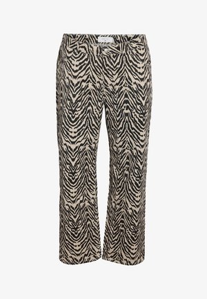 Beige ja musta kangaga, zeebrahalli mustri ja üle mõõtmete ümbrusõlgadega jakk ja püksid, kantud halli T-särgi kohal, millel on punane tekst. Kollased prillid täydentavad välimust.