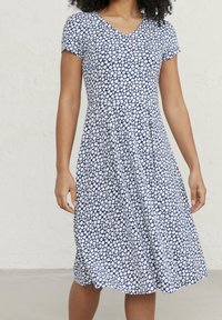 Modro-bílá květinová šaty s výstřihem do V, krátkými rukávy a rozšířenou sukní. Vyrobené z měkké tkaniny, s malým vzorem sedmikrásek.