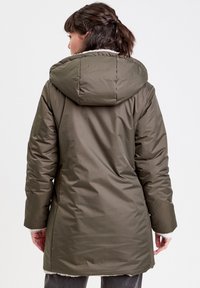 Doudoune olive avec une capuche, présentant un extérieur lisse et brillant et une doublure douce et texturée. Design longueur genou avec coutures latérales.