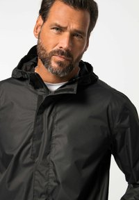 Black waterproof jacket with a zip front, adjustable hood, and soft texture. Features a minimalistic design and no visible patterns.