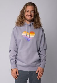 Lichtpaarse hoodie met een hartafbeelding voorzien van oranje, geel, wit, lavendel en donkerpaarse strepen. Inclusief een voorzak.