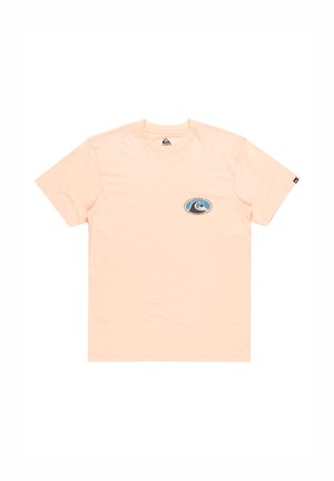 T-shirt en pêche clair en coton, avec un petit logo ovale représentant une vague et une montagne sur le côté gauche de la poitrine. Style col rond.