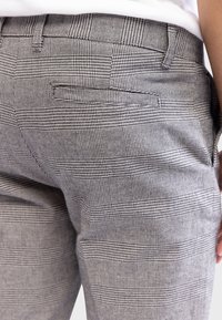 Gray checkered pants with a textured pattern, featuring a back pocket and structured waistband. Made from a lightweight fabric.