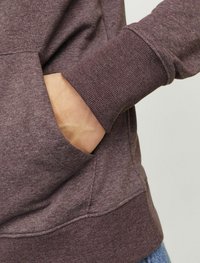 Purple sweatshirt featuring ribbed cuffs and a kangaroo pocket, made of soft, textured fabric with a casual, relaxed fit.