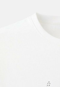 Witte katoenen t-shirt met een ronde hals en kleine strassaccenten vlakbij de onderste rechterkant. Soepele textuur, minimalistisch ontwerp.