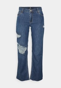 Jeans de ganga azuis com um corte relaxado, remendos desgastados nos joelhos e detalhes cosidos. Inclui fecho com botão e zip.