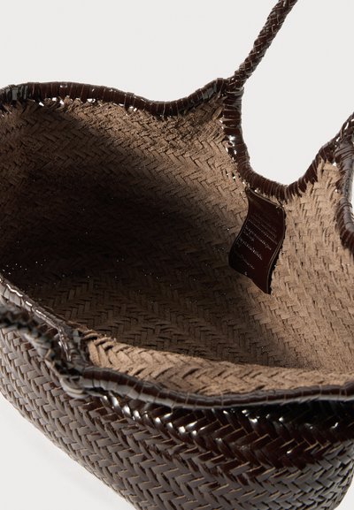 Καφέ πλεκτή τσάντα χειρός με γυαλιστερή φινίρισμα, παρουσίασε υφή στο εσωτερικό της και έχει μία ετικέτα μέσα. Το σχήμα είναι ανοιχτό και στρογγυλό στην κορυφή.