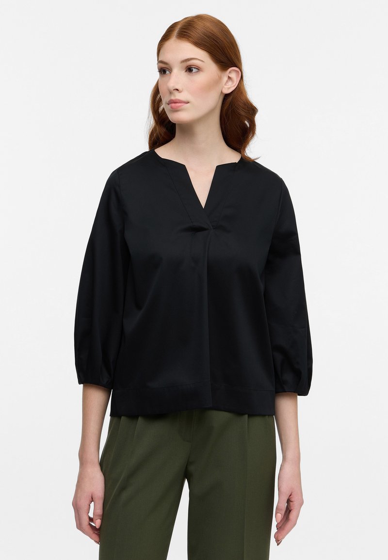 Blusa nera con scollatura a V e maniche a tre quarti a palloncino. Tessuto morbido, vestibilità comoda e dettaglio di cucitura sottile lungo la parte anteriore.