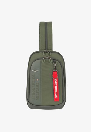 Borsa compatta a tracolla verde oliva con doppia cerniera, scritta "AERONAUTICA MILITARE", emblema alato e etichetta rossa "REMOVE BEFORE FLIGHT" attaccata.