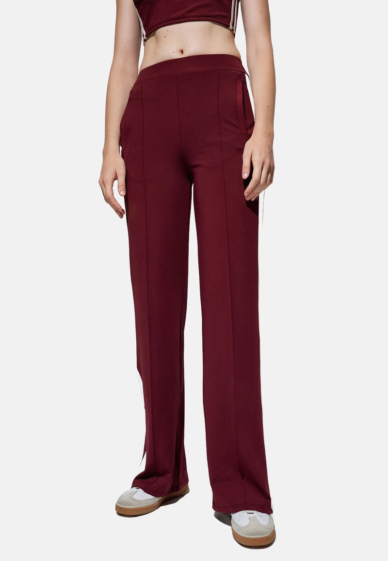 Bordeauxrode brede broek met een gladde textuur, voorzien van zijzakken en witte zijstrepen, aangevuld met een hoge tailleband.