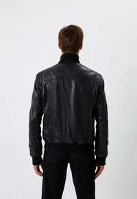 Czarna skórzana kurtka bombowca z prążkowanym kołnierzem i mankietami, o gładkiej teksturze i dopasowanej talii, prezentująca minimalistyczny design.