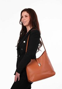 Hnědá kožená taška přes rameno se hladkým povrchem, zakřiveným tvarem, zlatými kovovými doplňky a jedním nastavovacím popruhem.