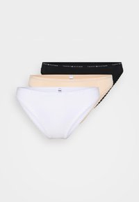 Trois paires de culottes pour femmes en noir, beige et blanc. Les matériaux sont lisses, avec des bordures en dentelle sur la paire noire et des tailles avec logo.