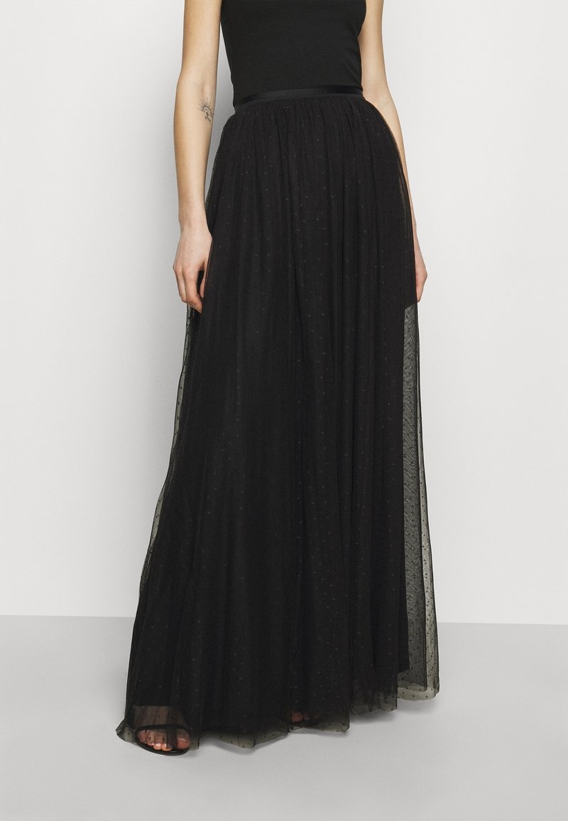 Czarna maksisuknia wykonana z lekkiego, przezroczystego materiału z teksturowanym wzorem kropek. Posiada pasek w talii w formie wstążki oraz luźny, zwiewny krój.