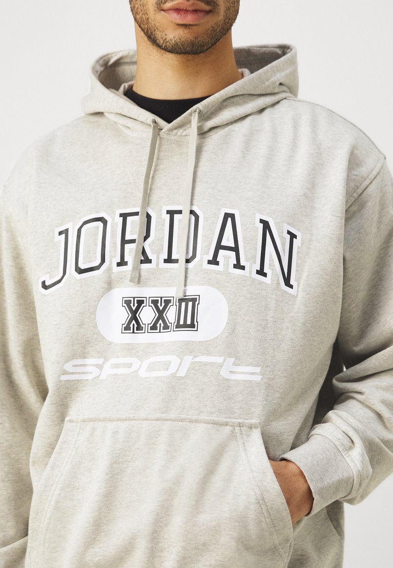 Hellgraue Kapuzenjacke mit "JORDAN" und "Sport" Grafiken, Kordelzugkapuze, Kängurutasche und gerippten Bündchen. Weicher, strukturierter Stoff.