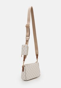 Sac bandoulière beige avec un tissu à motifs, doté d'un compartiment latéral, de quincaillerie dorée et d'une bandoulière détachable et réglable.