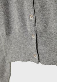 Grijze gebreide cardigan met een gestructureerde afwerking, voorzien van zes ronde knopen en een ronde zoomlijn. Zacht materiaal met een ribbelpatroon.
